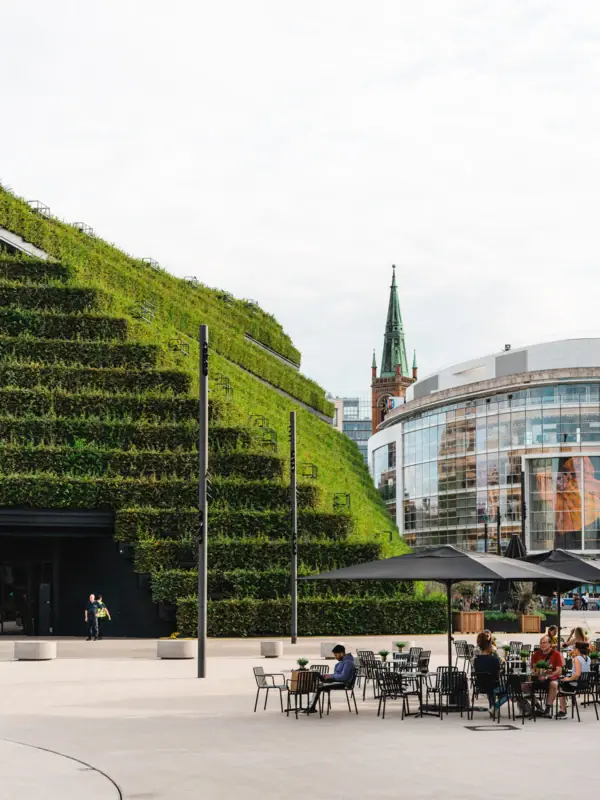 Ein Gebäude mit einer begrünten Wand in Düsseldorf und Menschen, die an Tischen sitzen.