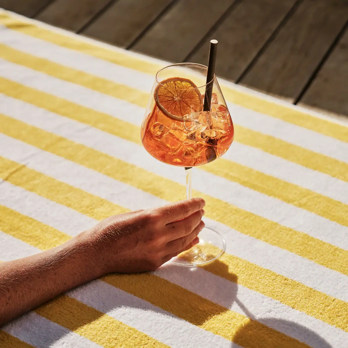 Eine Hand hält ein Glas Aperol Spritz.