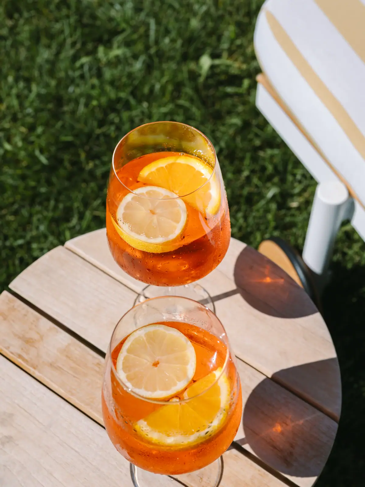 Zwei Gläser mit Aperol Spritz und Zitronenscheiben auf einem Tisch.