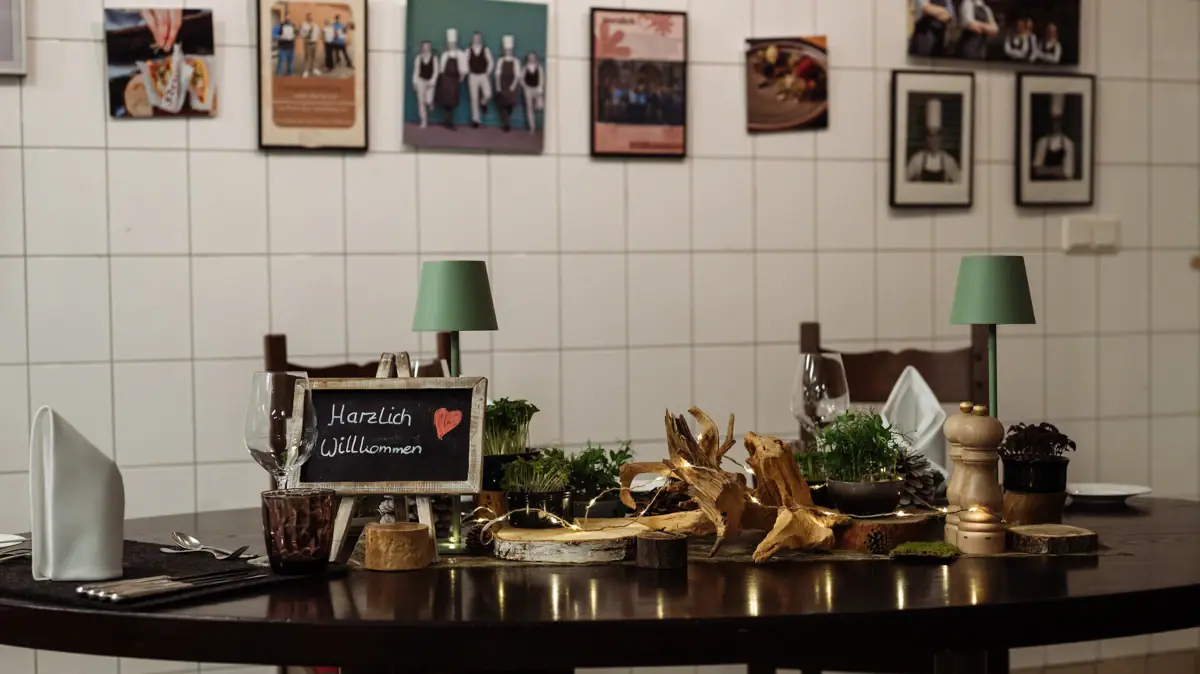 Ein gedeckter Tisch in einer Küche mit einem Schild und Gläsern darauf.