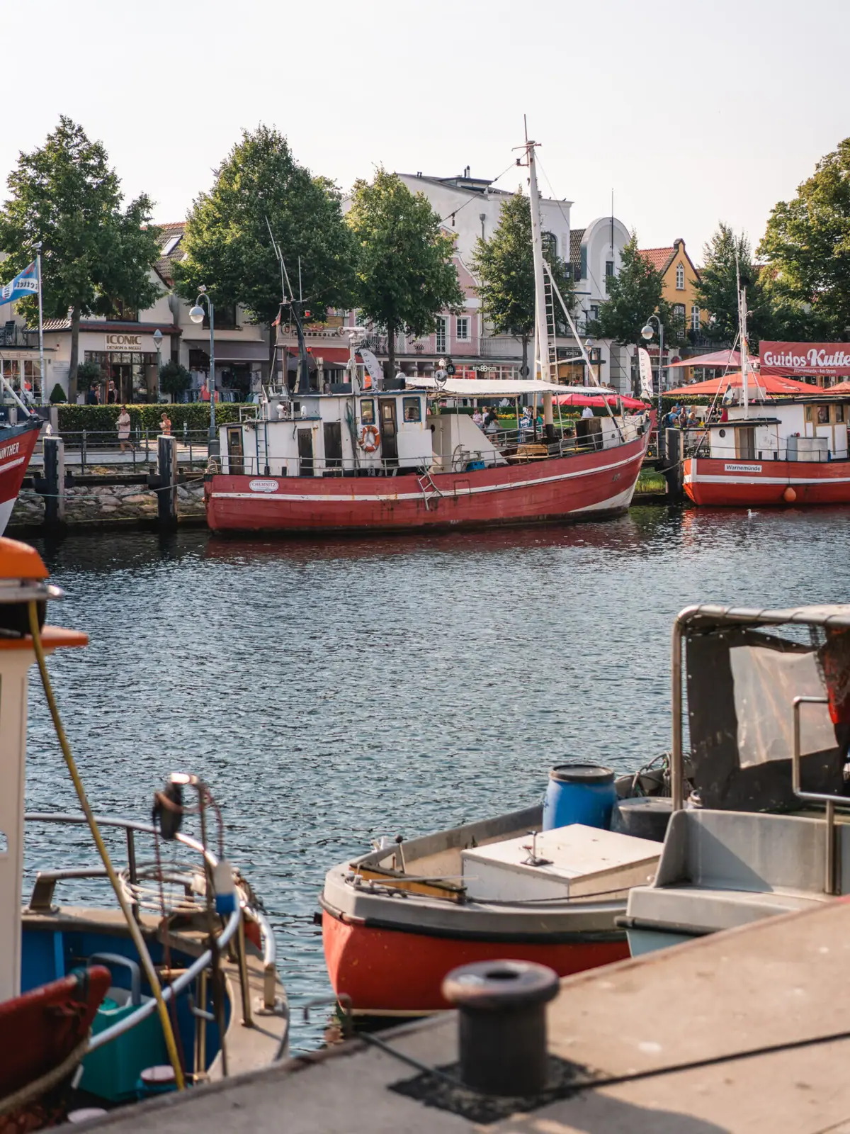 Der Alte Strom in Warnemünde mit Booten und Häusern im Hintergrund.