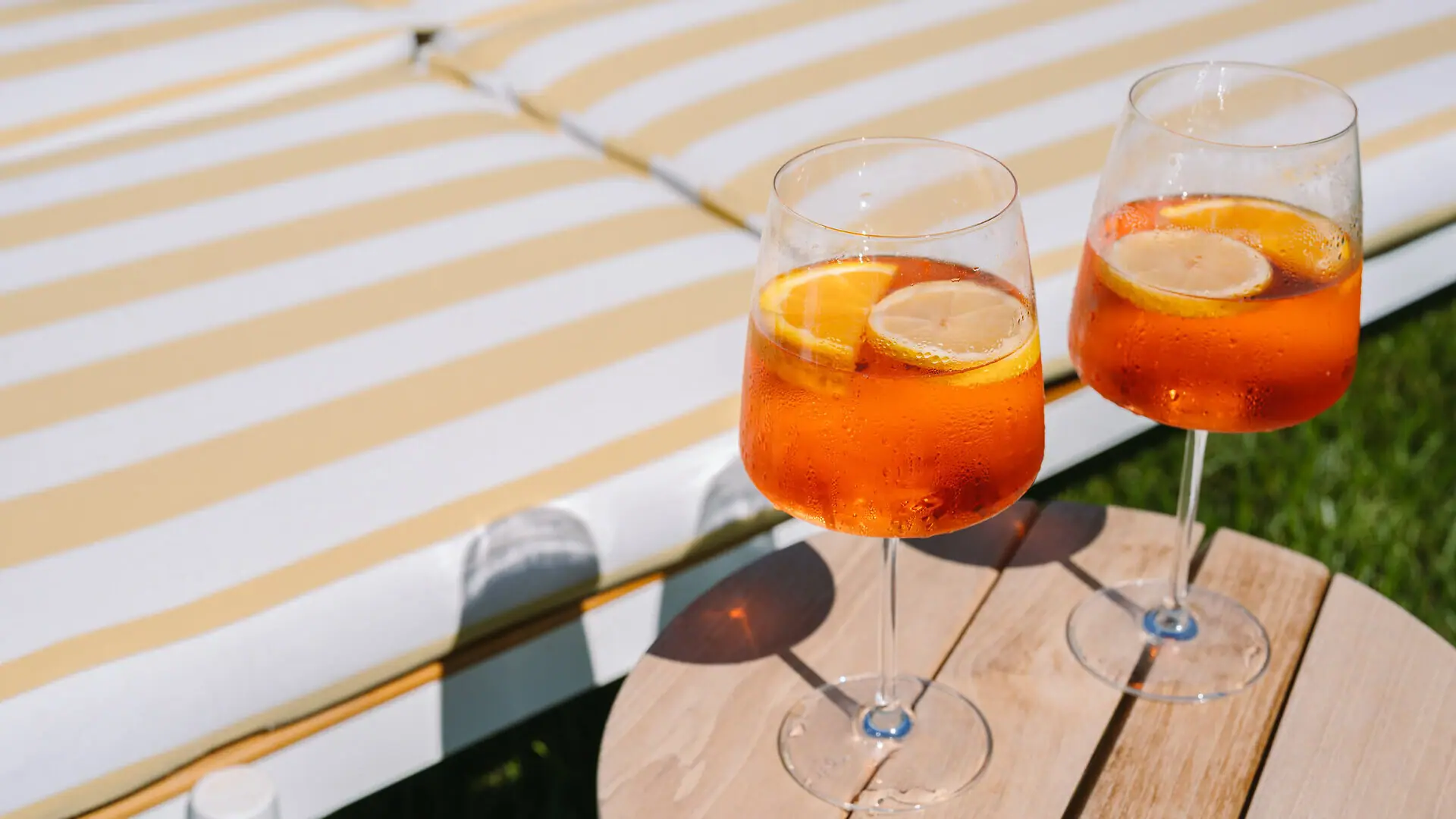 Zwei Gläser mit Aperol Spritz und Zitronenscheiben auf einem Tisch