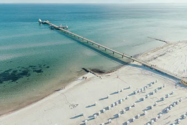 Der Strand von Grömitz von oben fotografiert mit türkis blauem Wasser und Strandkörben im Sand.