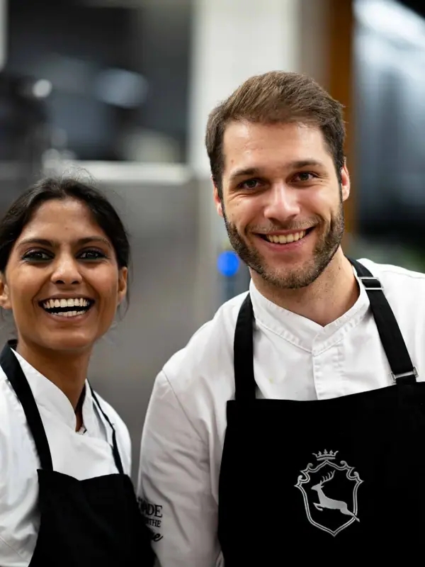 Ein Mann und eine Frau in Schürzen lächeln.