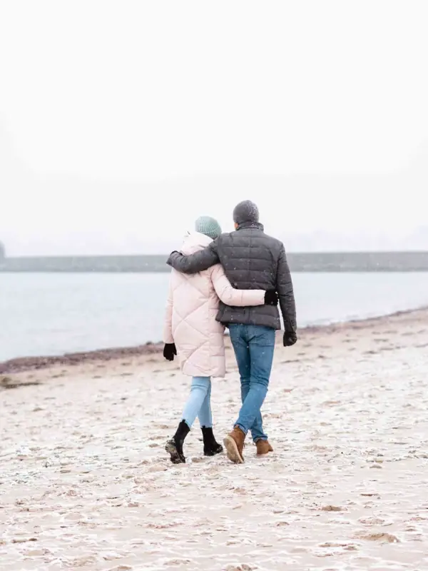 Ein Mann und eine Frau spazieren am Strand.