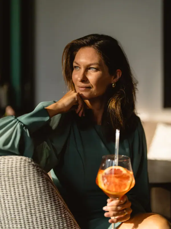 Frau sitzt in einer Hotelbar mit einem Cocktail.