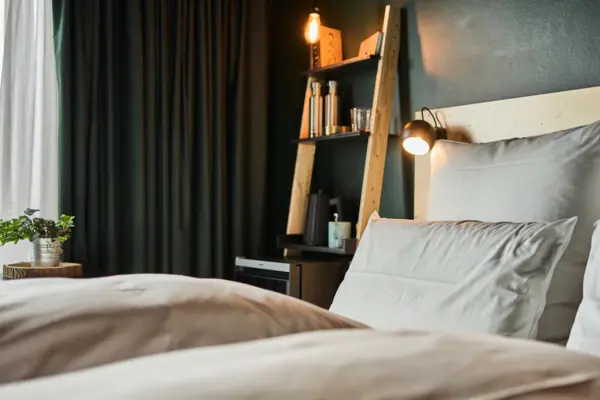 Ein Hotelzimmer im Urban Nature Hotel St. Peter-Ording mit einem Bett und einem Regal mit Lichtern.