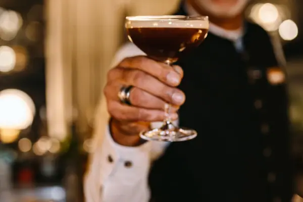 Ein Barkeeper hält ein Martini-Glas mit einem Espresso Martini.