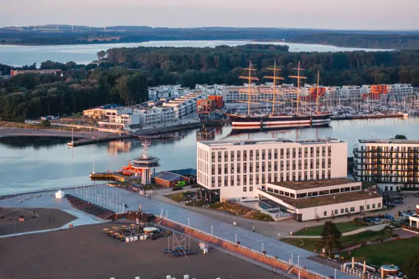Das aja Hotel in Travemünde direkt an der Promenade mit der Trave-Mündung, dem Priwall und dem Segelschiff Passat im Hintergrund. 