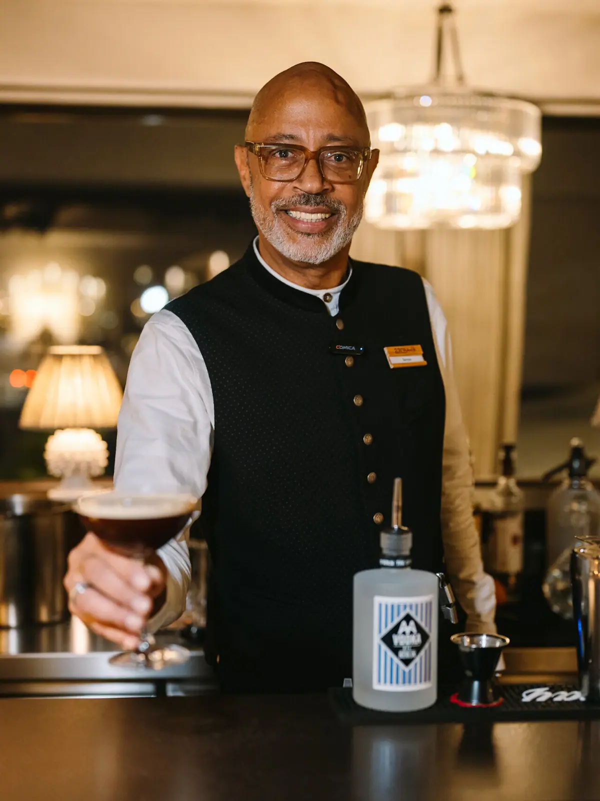 Ein Barkeeper hält einen Espresso Martini und lächelt.