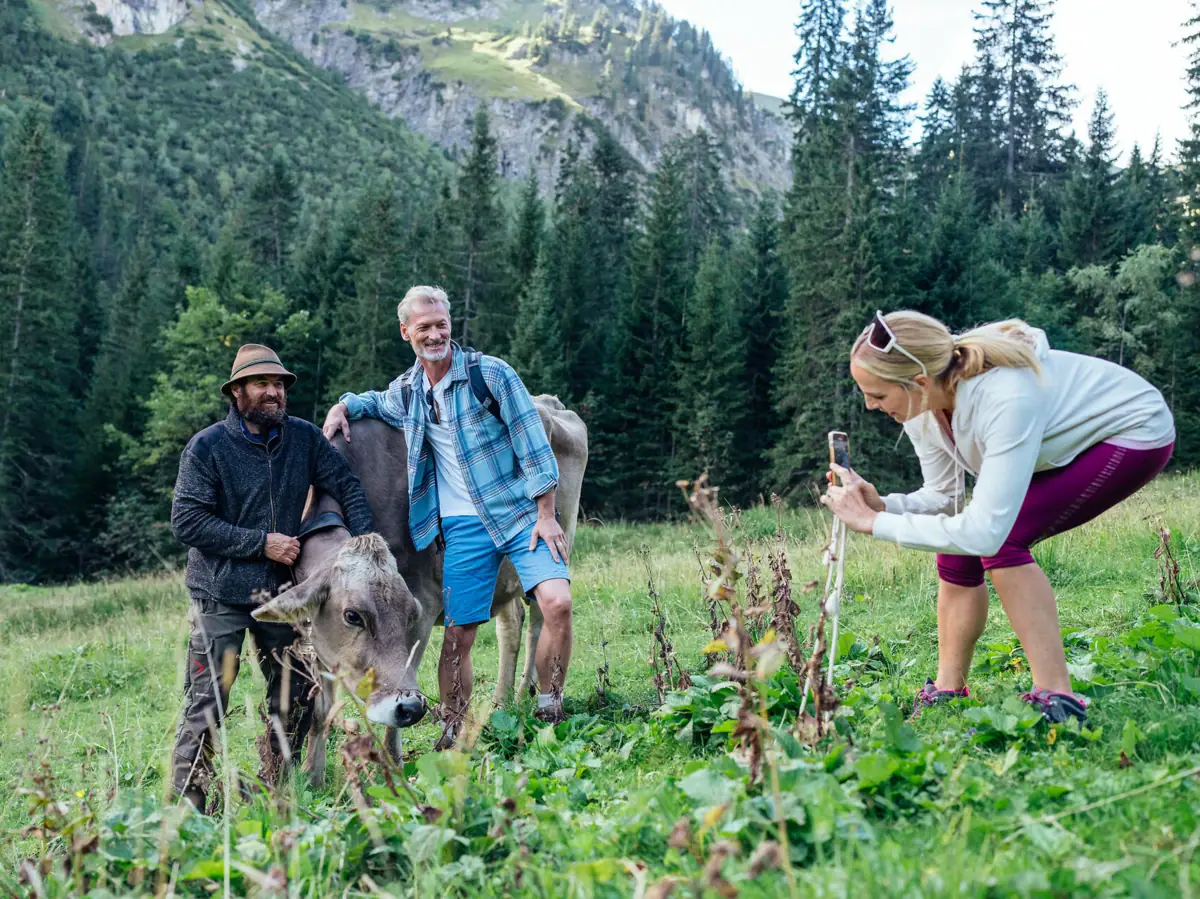 Eine Gruppe von Menschen steht auf einem Feld mit Kühen im Bärgunttal.