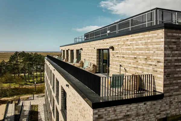 Ein Gebäude mit einem Balkon und Stühlen auf dem Dach.
