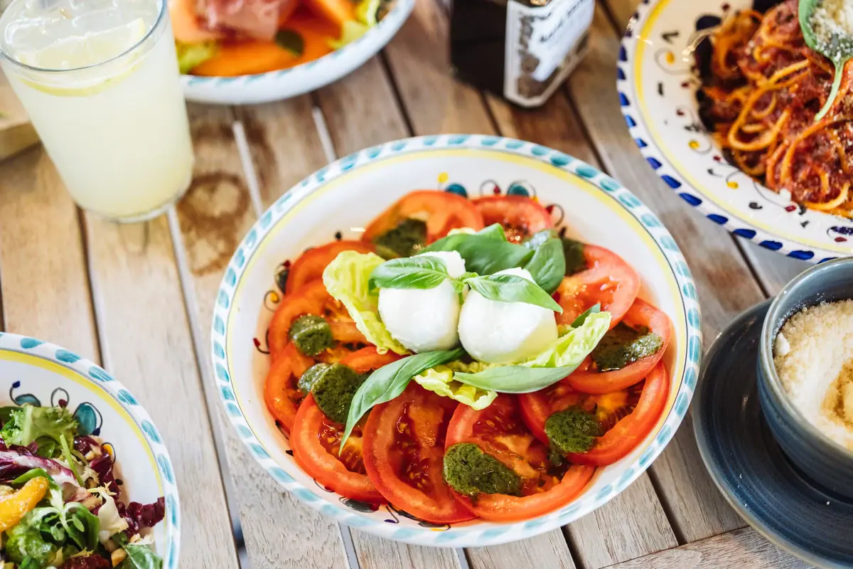Eine Schüssel mit Tomaten und Basilikum auf einem Tisch.