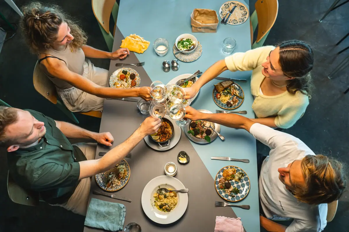 Eine Gruppe von Menschen sitzt an einem Tisch mit Tellern voller Essen und Gläsern im Auntie Clara Restaurant in St. Peter-Ording.
