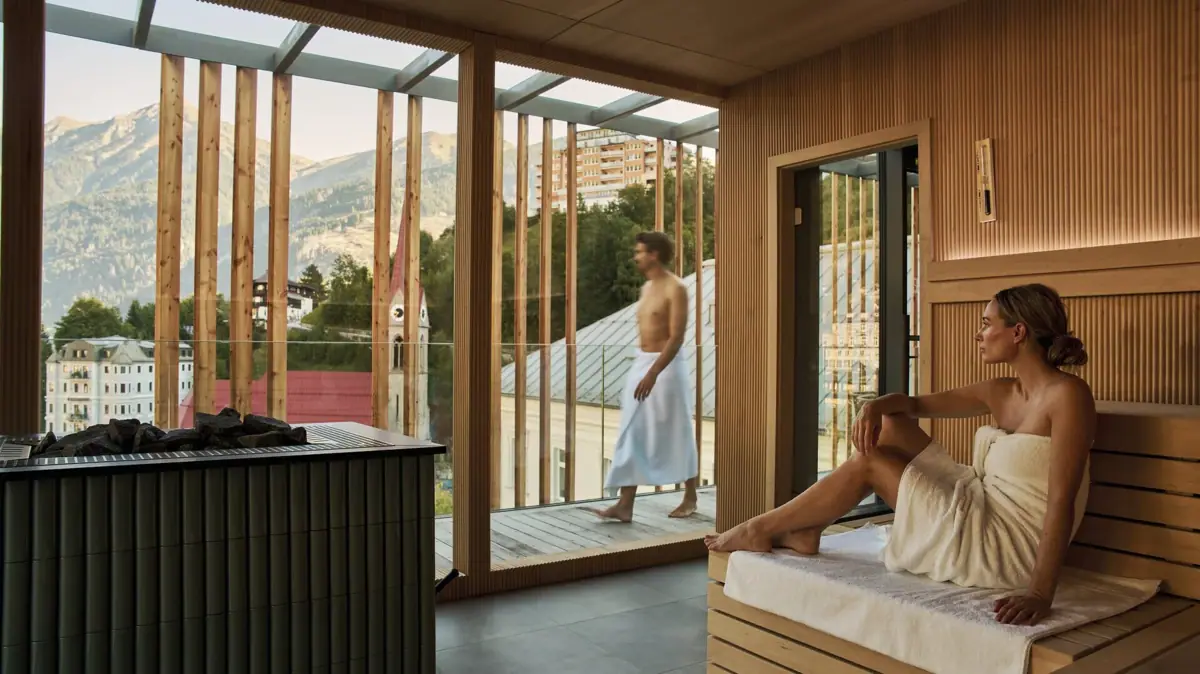 Eine Frau sitzt in einer Sauna und schaut nach draußen.