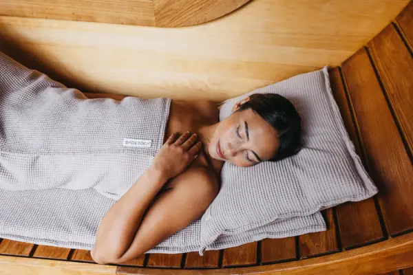 Eine Frau liegt in einer hölzernen Sauna.