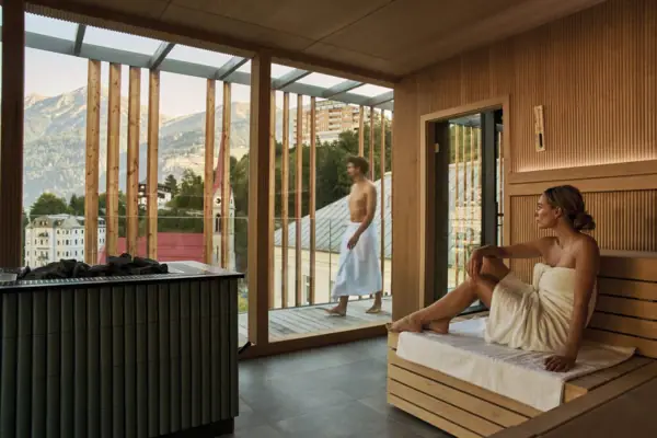 Eine Frau sitzt in einer Sauna und schaut nach draußen.