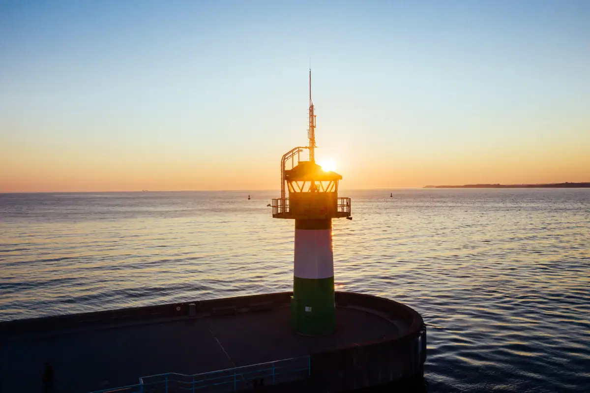 Ein Leuchtturm auf einem Steg im Wasser.