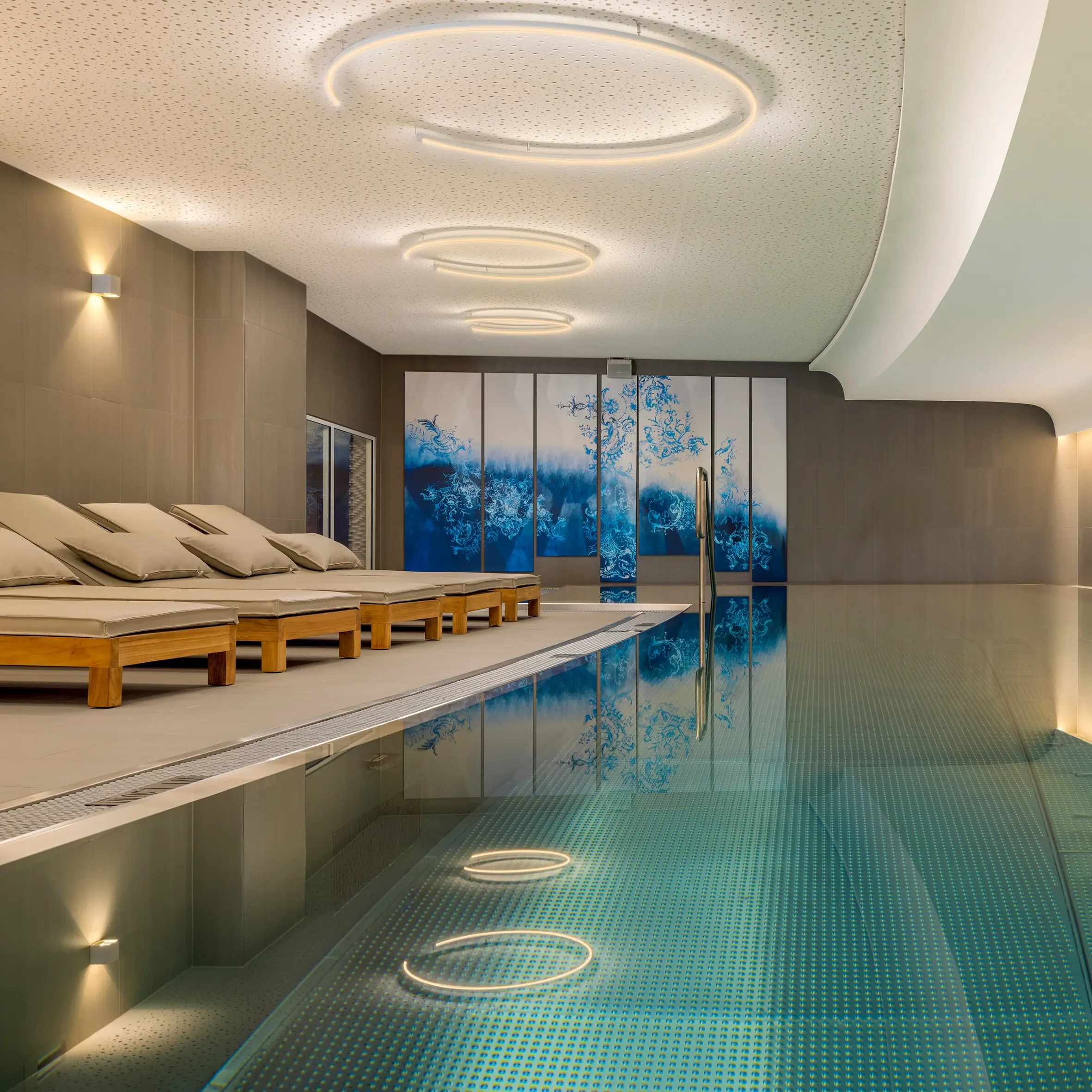Der Wellnessbereich im A-ROSA tegernsee mit einem Indoorpool und Liegen.