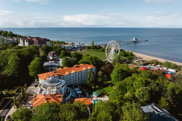 Das A-ROSA Strandidyll Heringsdorf neben einem Riesenrad und der Ostsee dahinter.