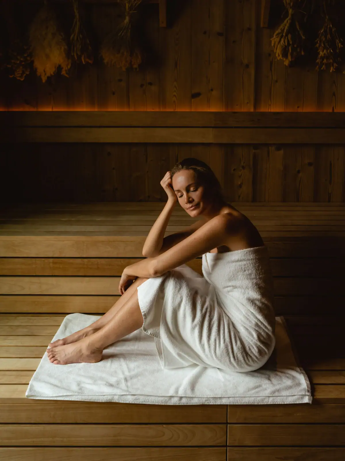 Eine Frau sitzt auf einem Handtuch in einer Sauna.