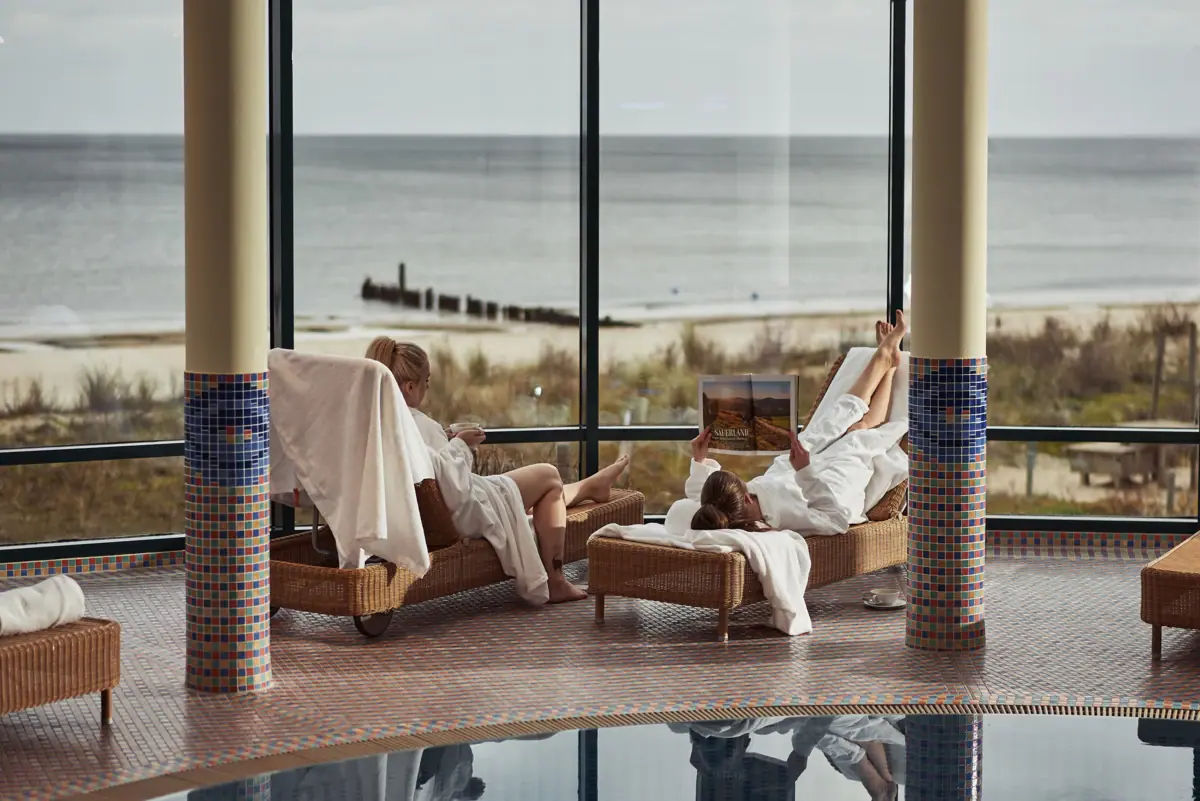 Zwei Menschen liegen im SPA Bereich im aja Bansin mit Blick auf die Ostsee.