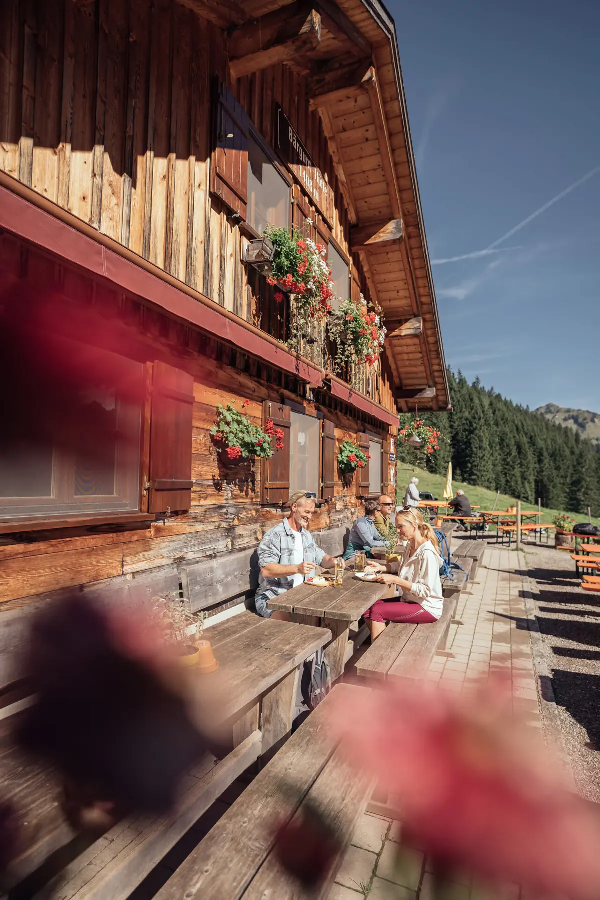 Menschen sitzen an einem Tisch vor der Bärgunthütte.
