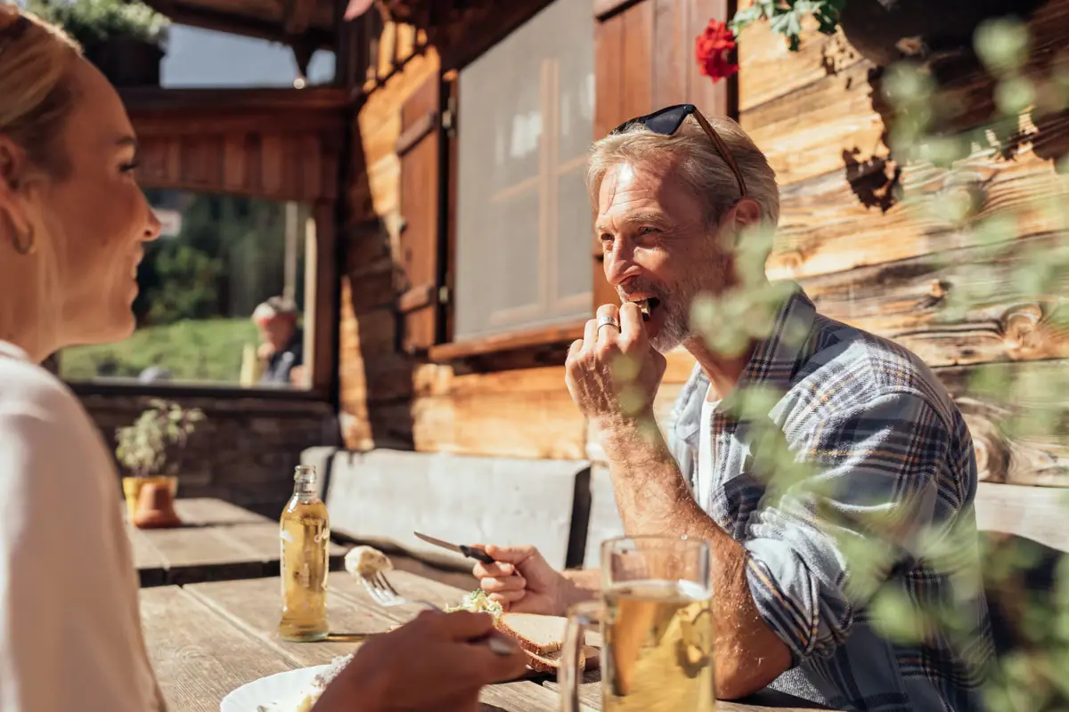 Mann isst Essen an einem Tisch in der Bärgunthütte.