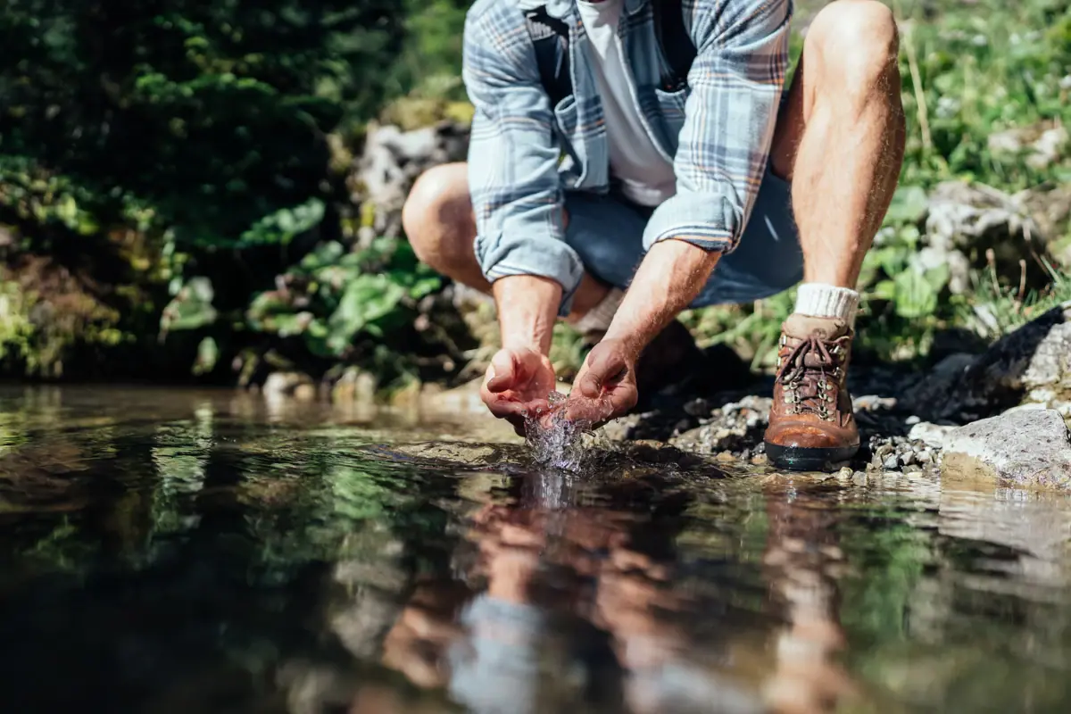 Ein Mann hockt in einem Wasserstrom.