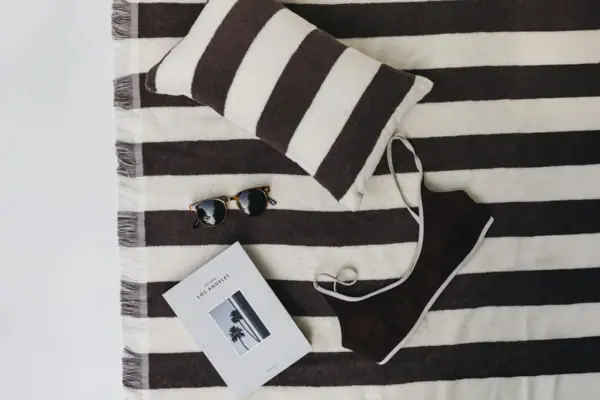 Schwarz-weiß gestreifte Decke mit einem Kleidungsstück und Sonnenbrille.