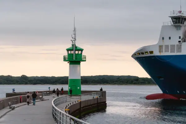 Ein grüner und weißer Leuchtturm neben einem großen Schiff an einem Pier.