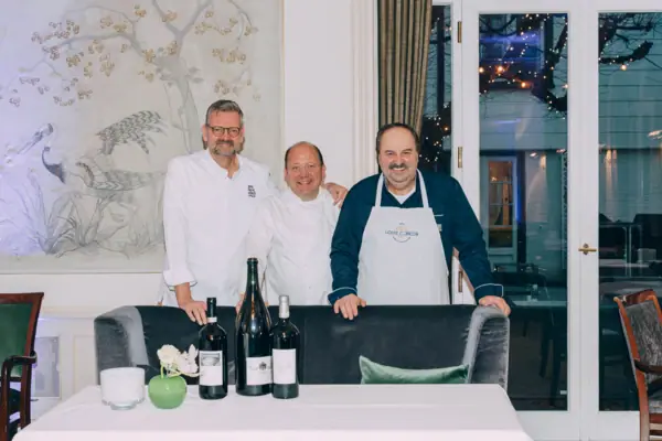 Eine Gruppe von Männern steht vor einem Tisch mit Weinflaschen.