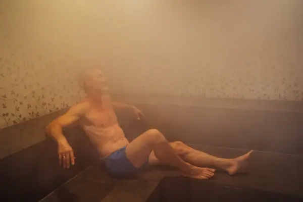 Ein Mann sitzt in einem Dampfbad.