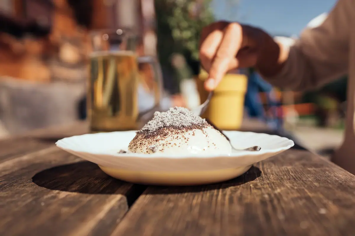Eine Hand hält einen Löffel über einem Germknödel in der Bärgunthütte.