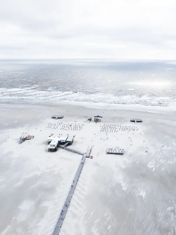 Strand von St. Peter-Ording mit einem Pier und Menschen darauf im Winter an der Nordsee.