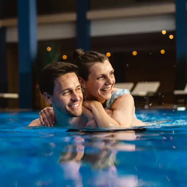 Ein Mann und eine Frau im Pool, beide lächeln.