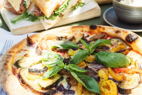 Pizza mit Gemüse und Basilikum auf einem Tisch