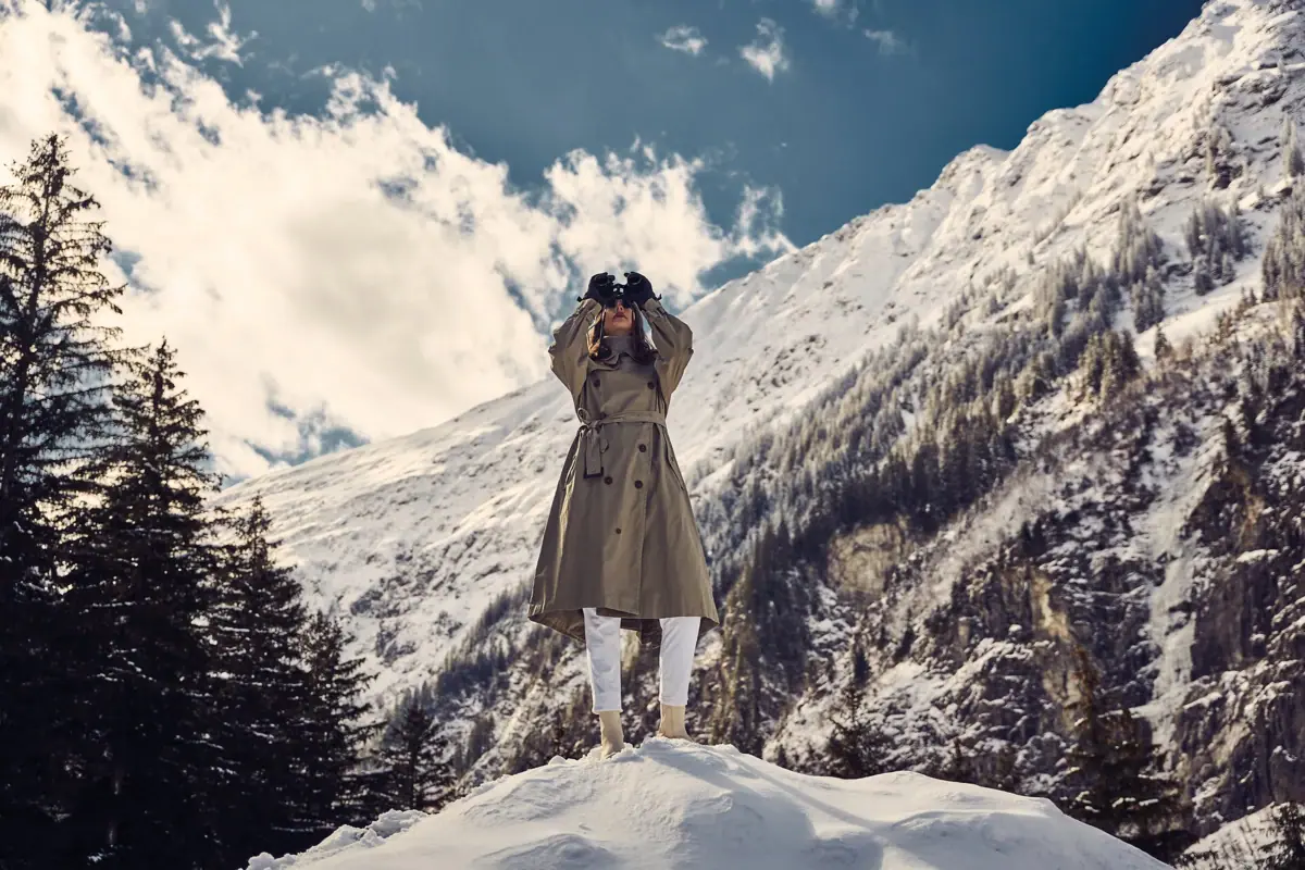 Eine Frau steht auf einem verschneiten Berg mit Fernglas.