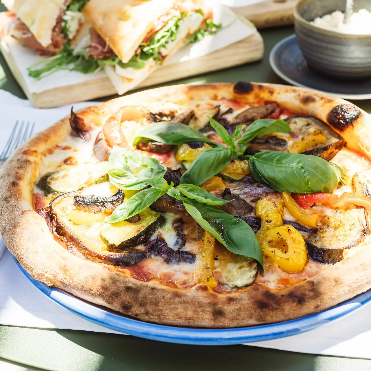 Pizza mit Gemüse und Basilikum auf einem Tisch