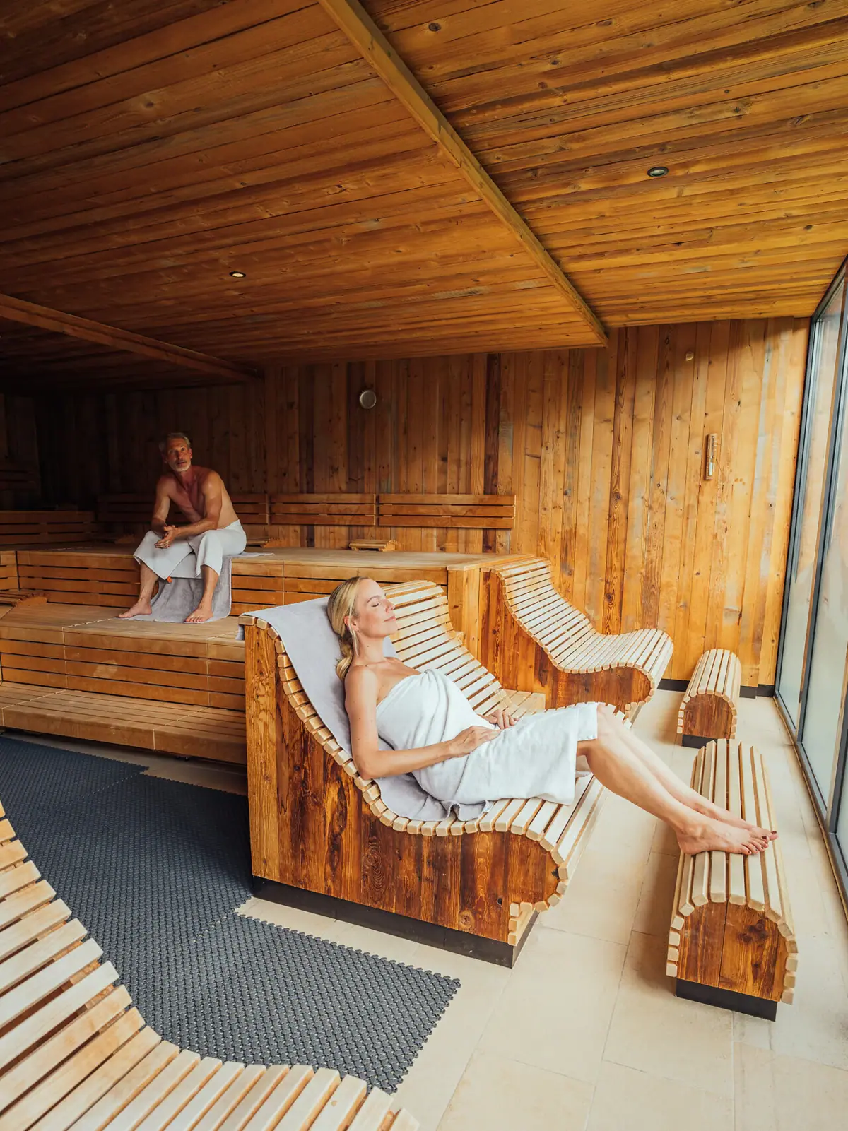 Eine Frau in einem Handtuch auf einer Bank in der Sauna.