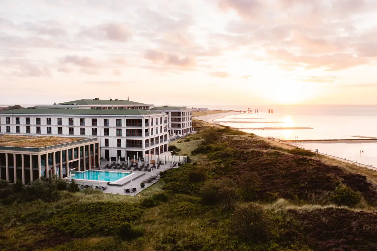 Das A-ROSA Sylt mit Pool direkt an den Dünen gelegen mit dem Strand und der Nordsee daneben.