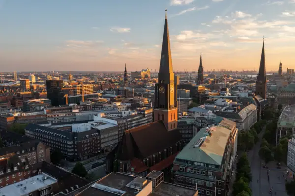 Stadtansicht von Hamburg mit hohem Kirchturm bei Sonnenuntergang.
