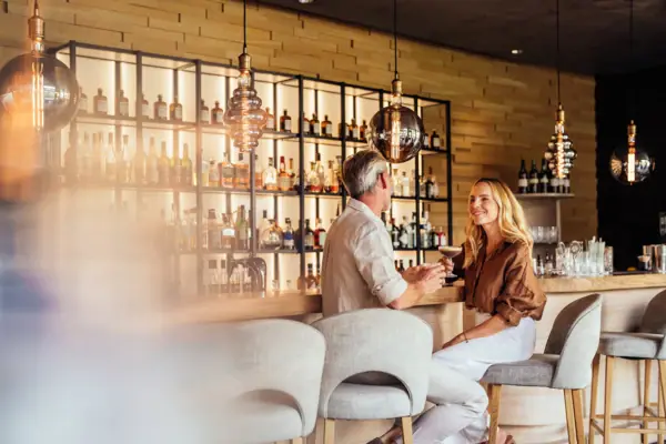 Ein Mann und eine Frau sitzen an der Hotelbar im A-ROSA Ifen Hotel im Kleinwalsertal.