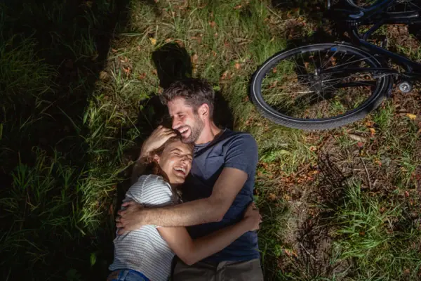 Ein Mann und eine Frau liegen auf Gras neben einem Fahrrad.